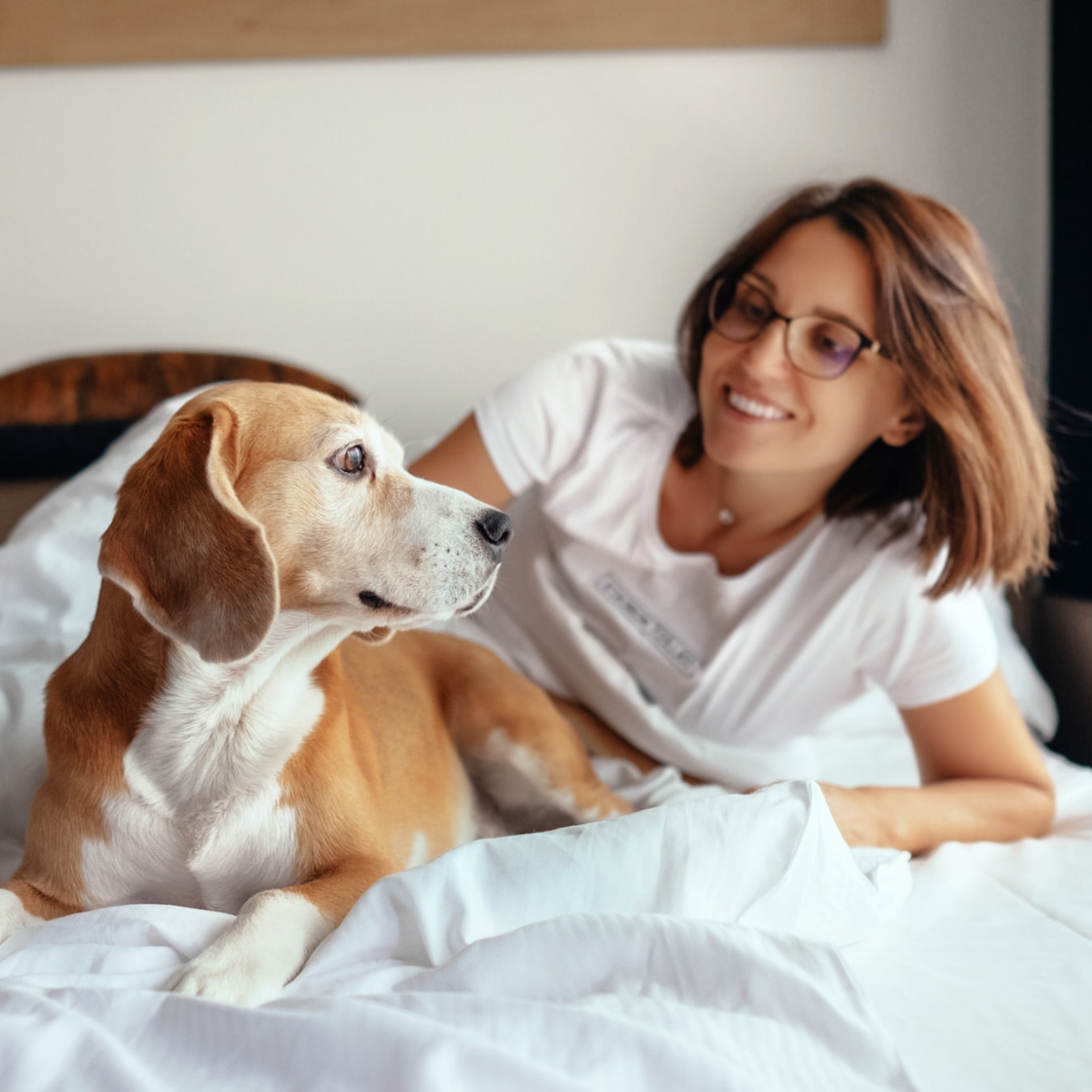 a woman and a dog laying on a bed